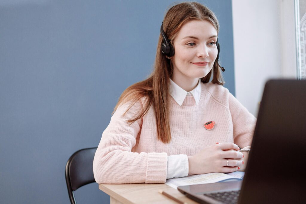 pexels-photo-6502997-6502997 Smiling woman in pink sweater working remotely as a customer service agent.